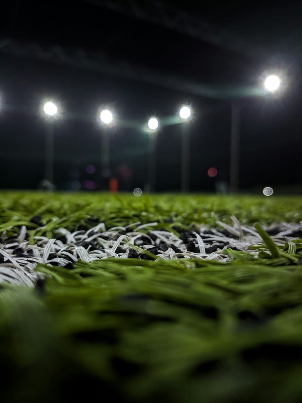 Artificial turf at night, floodlights glowing over the pitch.