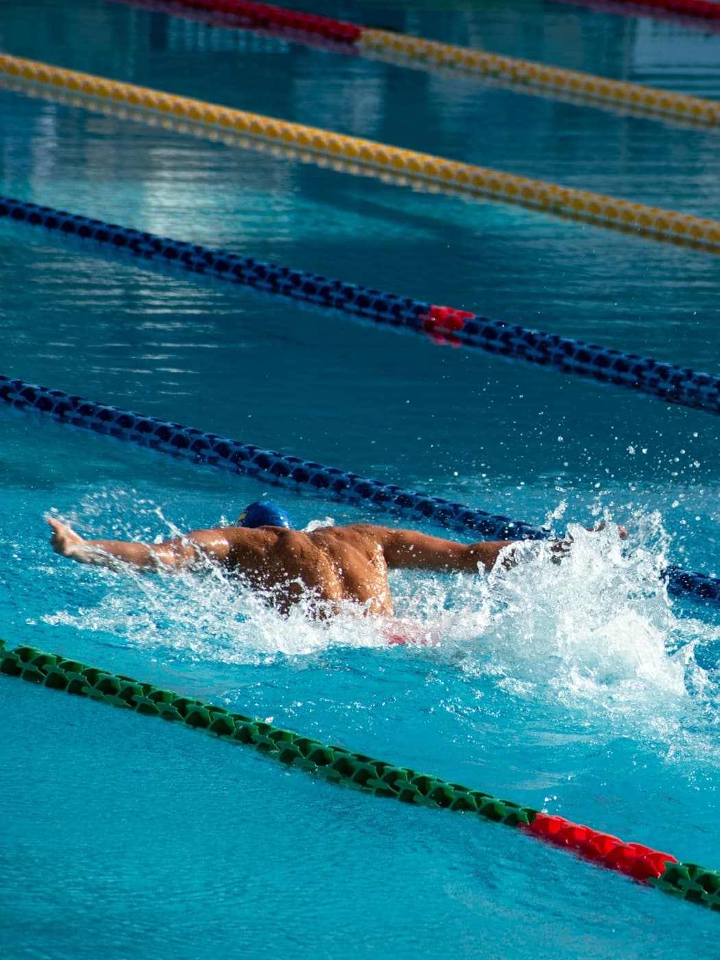 A swimmer mid-stroke in a lane of an outdoor pool.